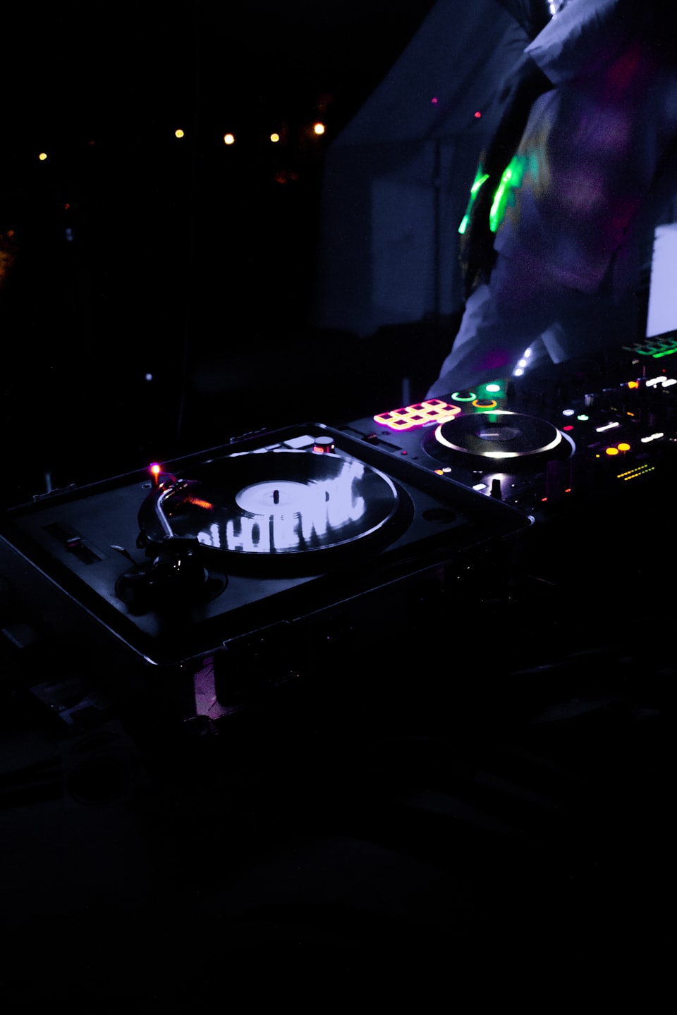 DJ mixing music on turntables with colorful lights.